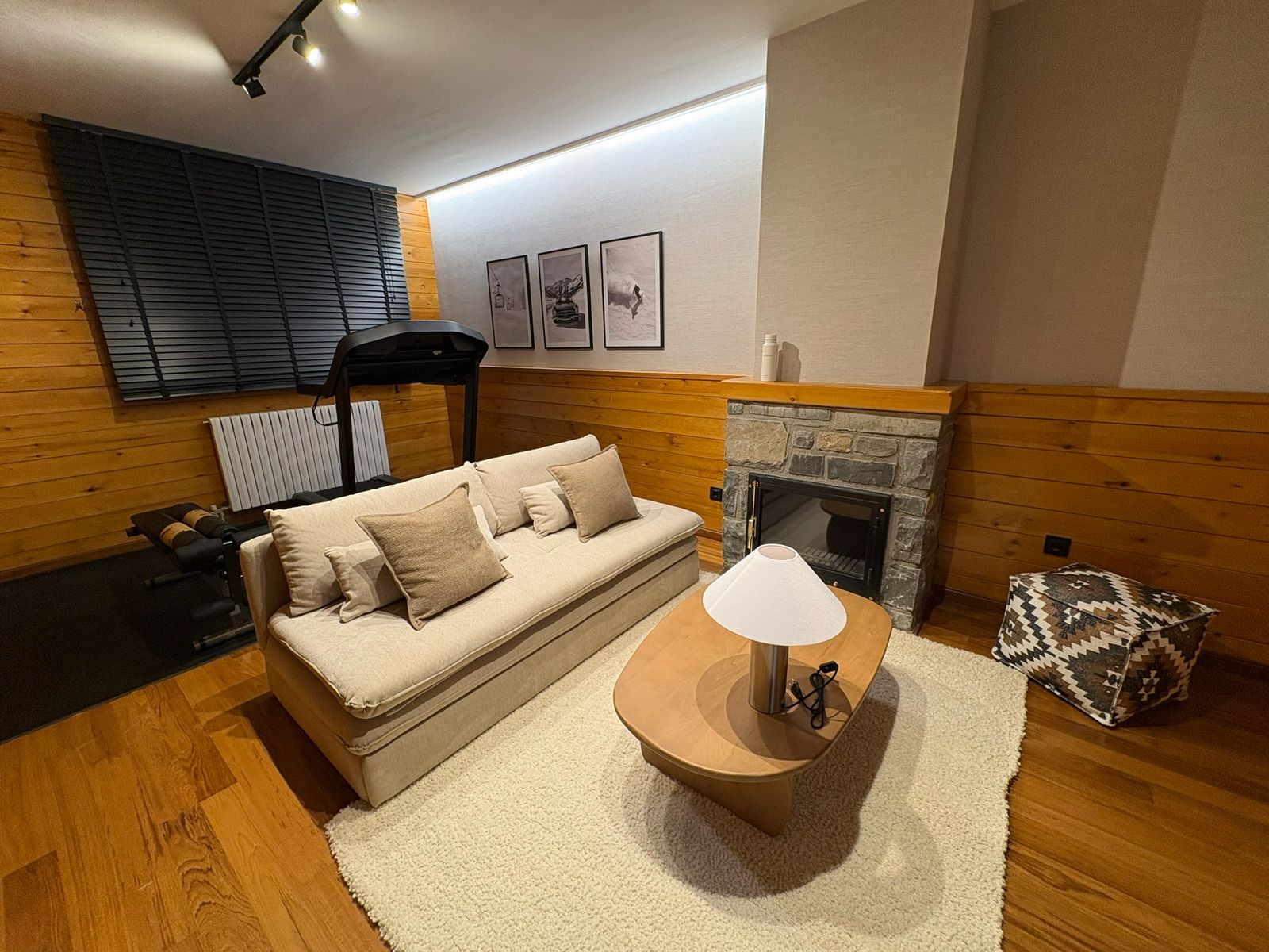 Salón en Formigal con chimenea, sofá claro y revestimiento de madera