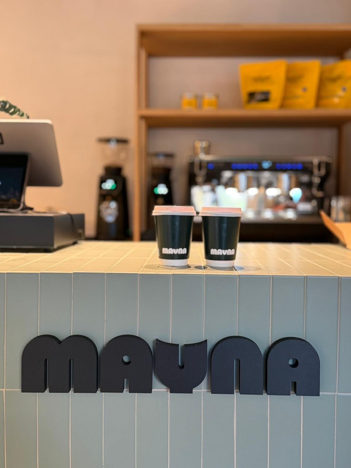 Barra de cafetería Mauna con estantes amarillos y frente de madera