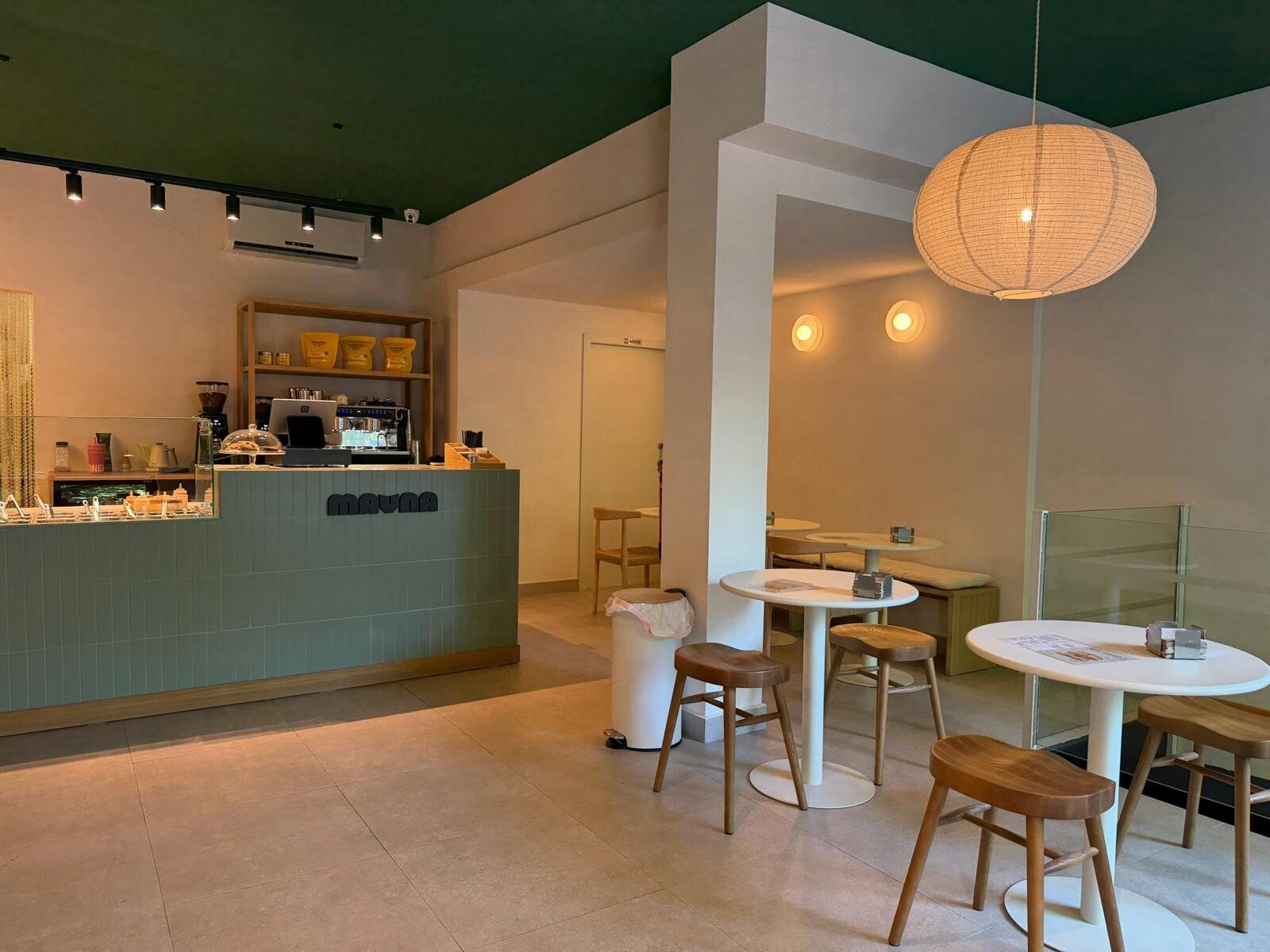 Cafetería Mauna con mostrador verde y lámparas de mimbre