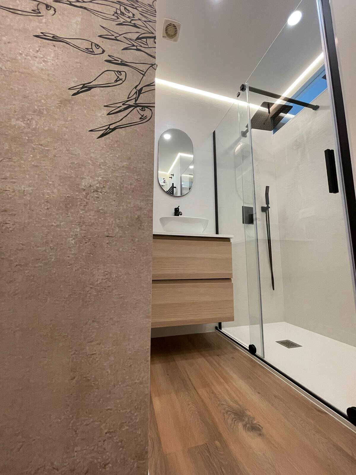 Baño de vivienda en Madrid con lavabo suspendido y mampara de cristal