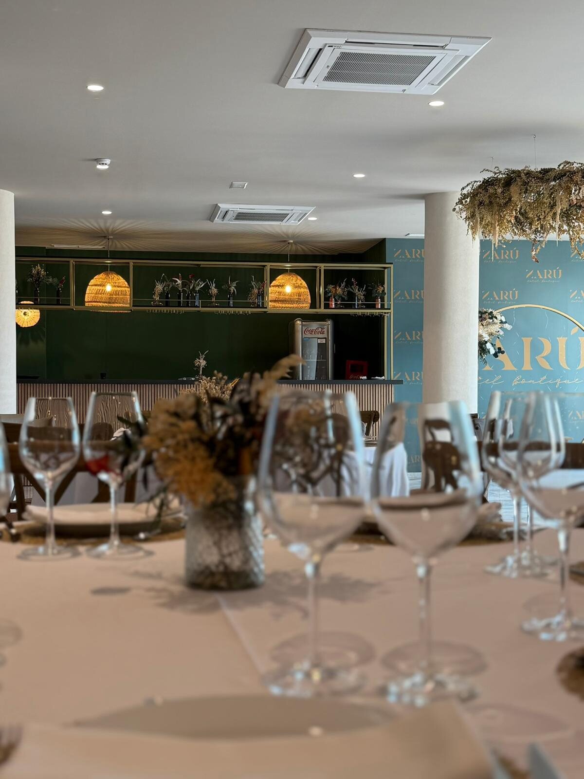 Restaurante del hotel Zarú con mesas, sillas tapizadas y barra verde
