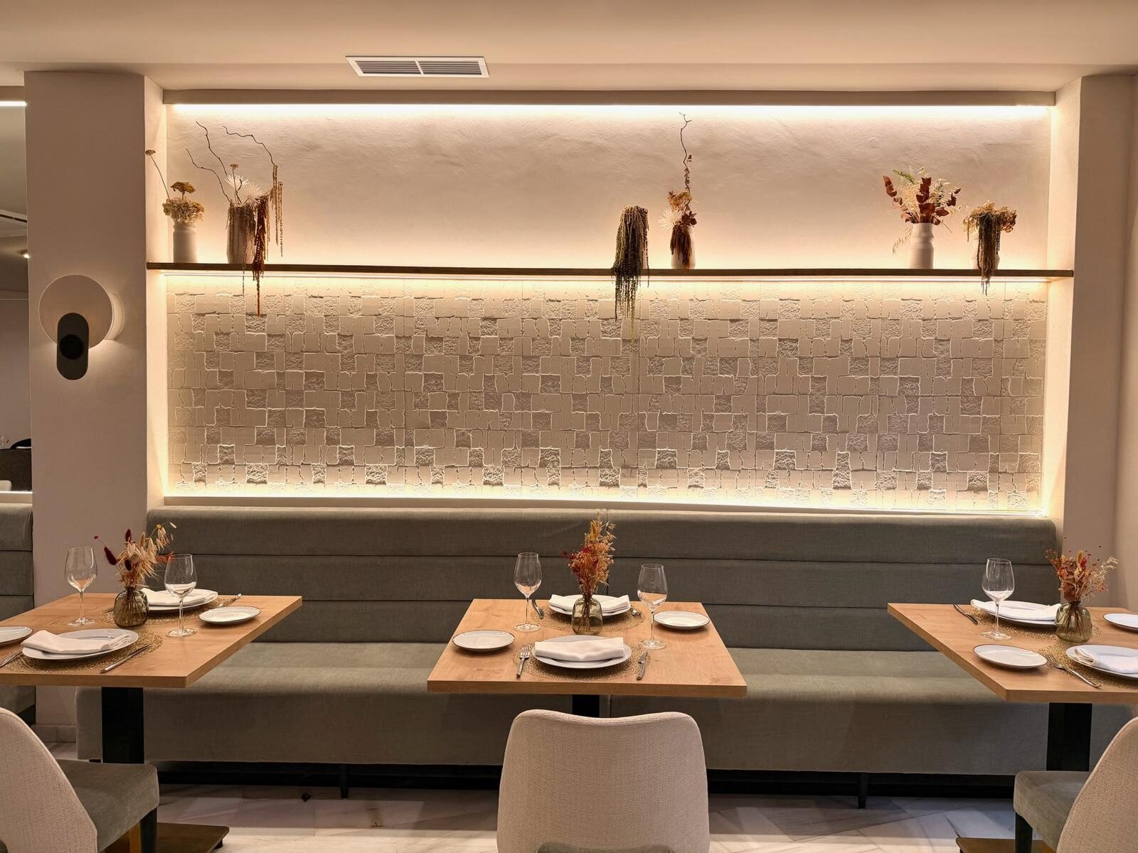 Rincón de restaurante Zarú con banco tapizado y pared retroiluminada