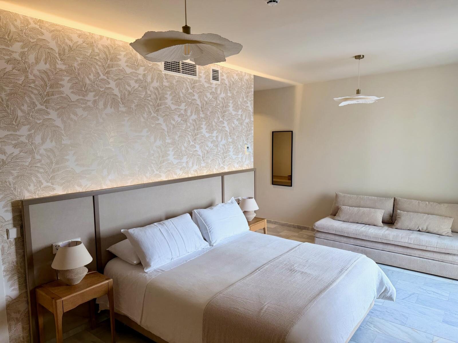 Dormitorio del hotel Zarú con cabecero iluminado y sofá claro