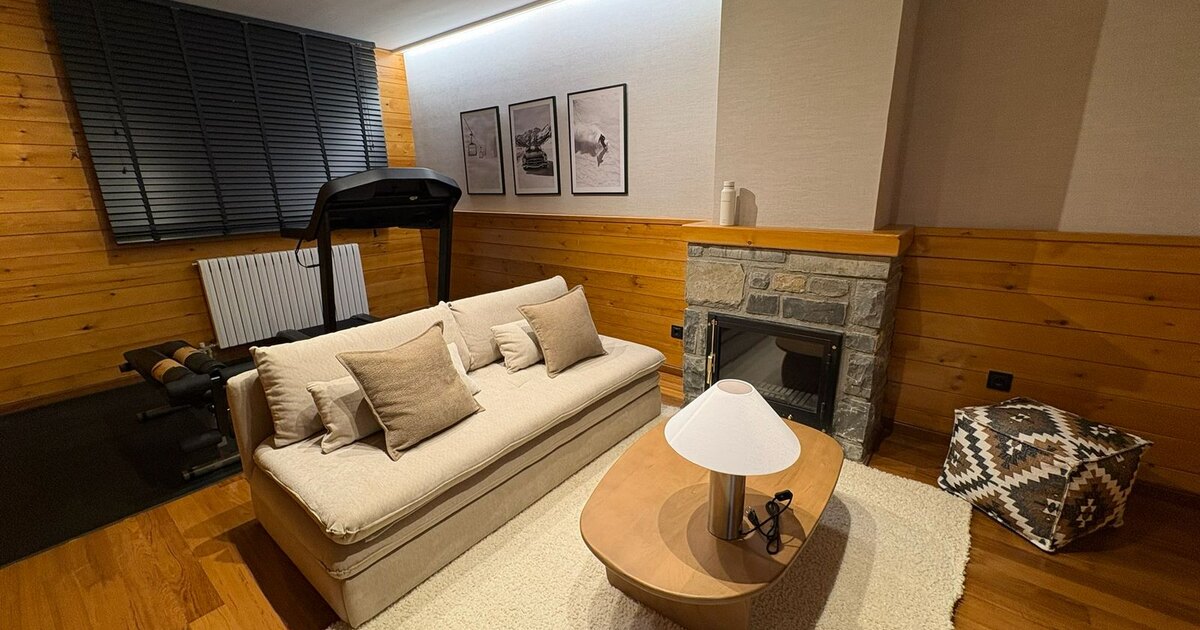 Salón reformado de vivienda en Formigal con chimenea y revestimientos de madera