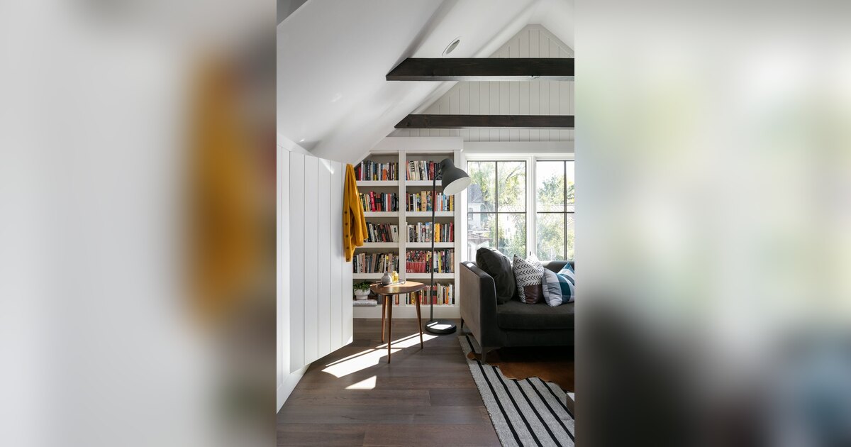 Salón luminoso de dimensiones reducidas con estantería, sofá y ventanas